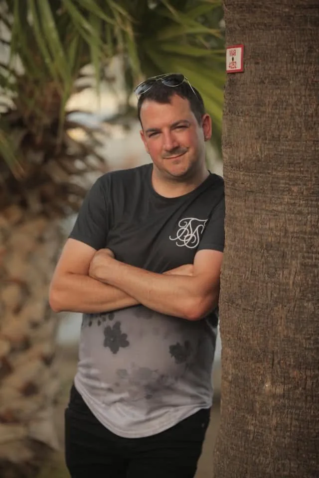 Matt standing beside a palm tree while on holiday